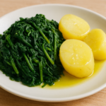 Un piatto di preboggión con erbe spontanee lessate e patate a pasta gialla, condite con olio e limone.