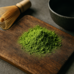 Polvere di matcha verde brillante con frustino di bambù e ciotola giapponese su un tagliere di legno.