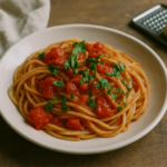 Un piatto di spaghetti alla picchio pacchio con pomodori a pezzi e basilico fresco, servito in una semplice ceramica.